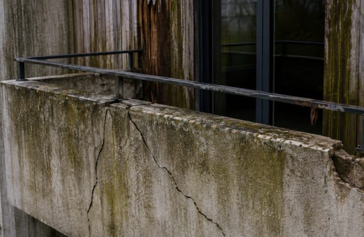 Balcon en béton fissuré à la jonction avec la façade