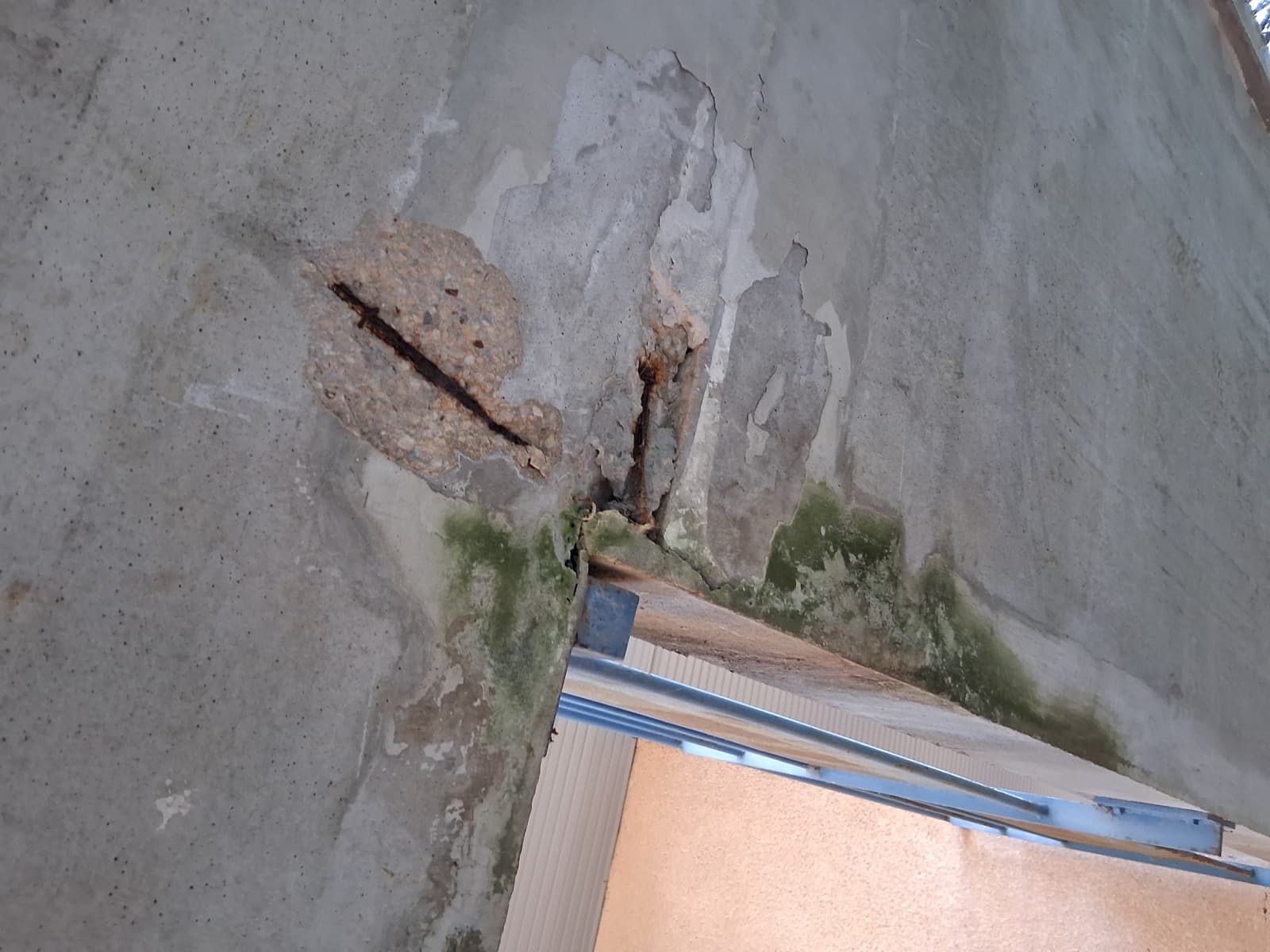 Sous-face de balcon en béton avec éclat d'enrobage et armature fortement corrodée apparente