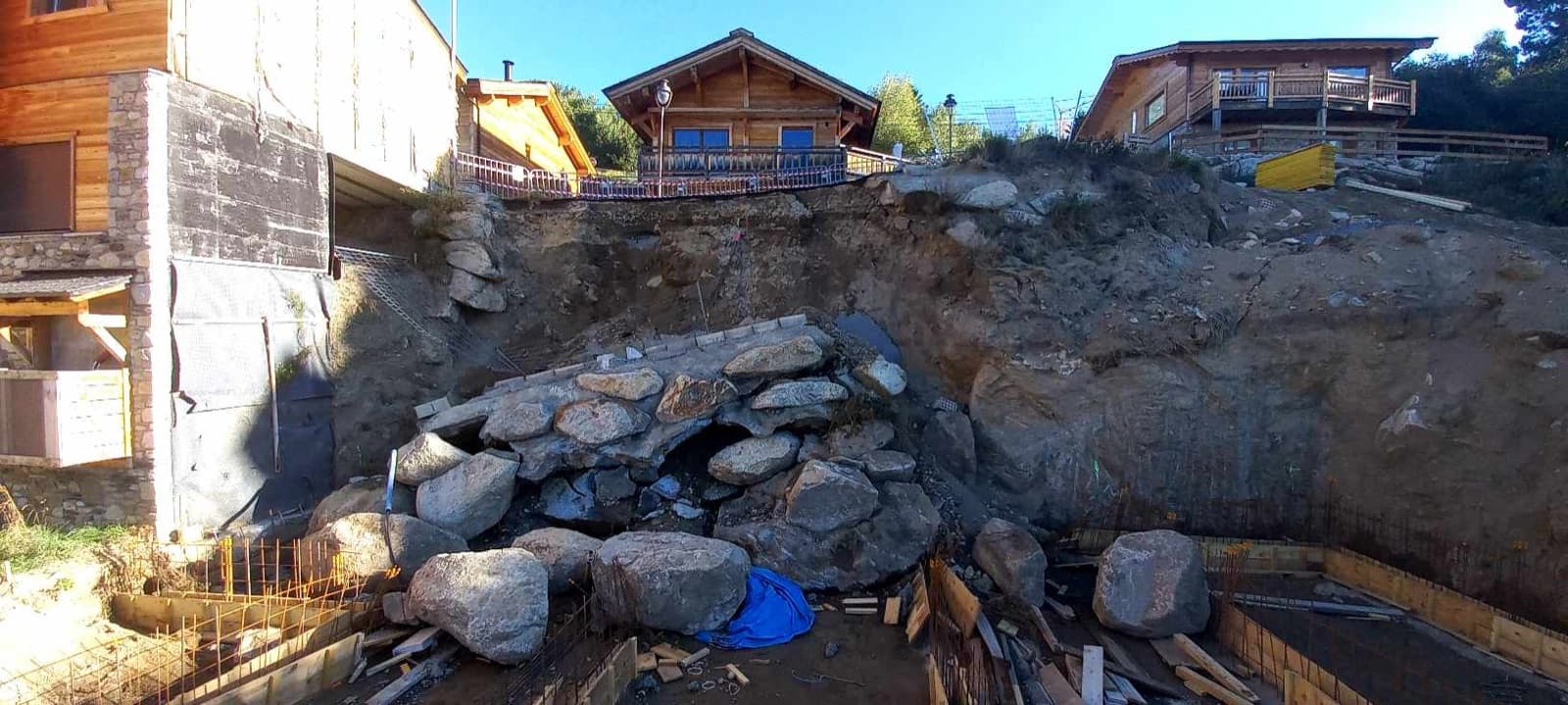 Mur de soutènement effondré sur un chantier, blocs de pierre éboulés au pied du talus