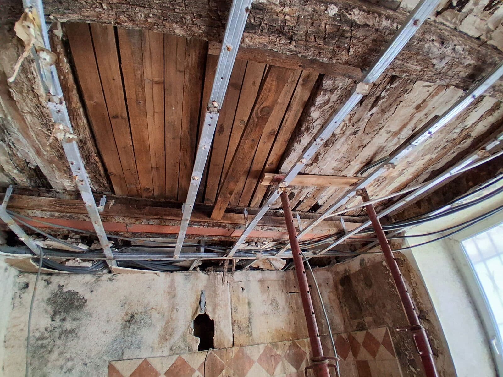 Solives en bois d'un plancher ancien avec câbles techniques fixés en sous-face et étaiement métallique provisoire
