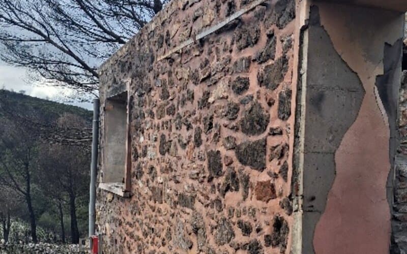 Mur en pierre rougi par la chaleur d'un incendie, avec ouverture de fenêtre